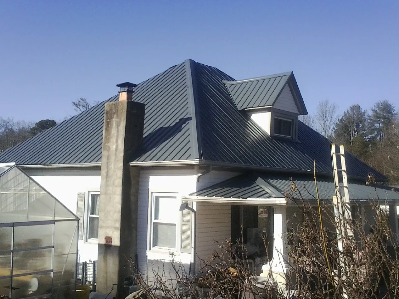Dark blue standing seam metal roof on a white farmhouse with dormer — Slate & Tile Roof Repair by Roofing Brothers in Turlock