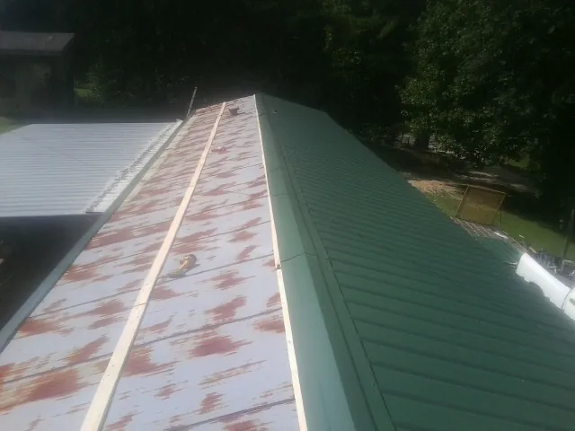 Old rusted panels beside newly installed green metal roofing — Wind Damage Roof Repair by Roofing Brothers in Turlock
