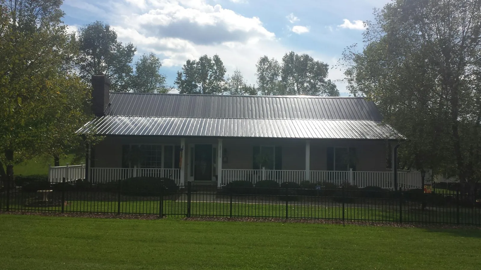 Gray metal roof on a brick ranch with a full width front porch — Gutter Guard Installation work by our crew in Turlock