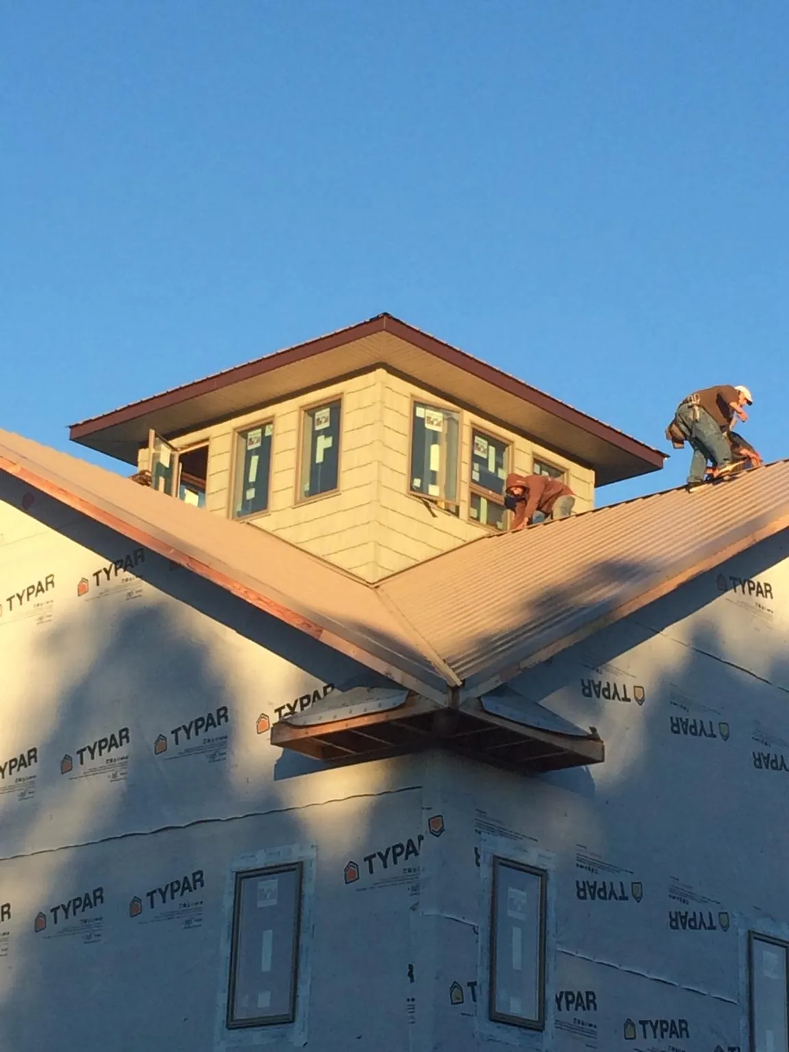 Roofers working around a rooftop cupola on a new metal roof at sunset — Roof Waterproofing in Turlock by Roofing Brothers